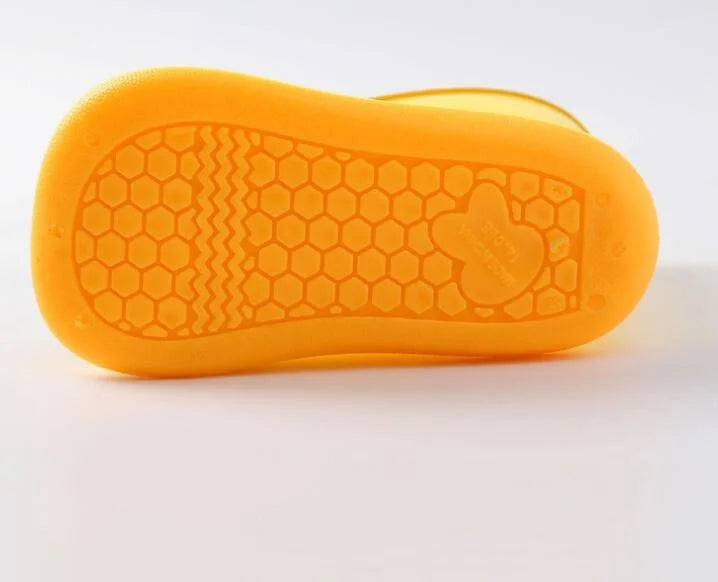 An orange, flexible silicone rain boot sole with a textured pattern and a molded foot shape.