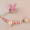 Pink silicone pacifier clip with a wooden bead necklace for a baby