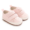 A pair of pink baby first walkers with soft soles and elasticized straps.