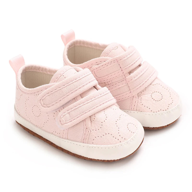 A pair of pink baby first walkers with soft soles and elasticized straps.