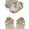 Pair of beige baby girl shoes with a satin bow detail and soft anti-slip sole