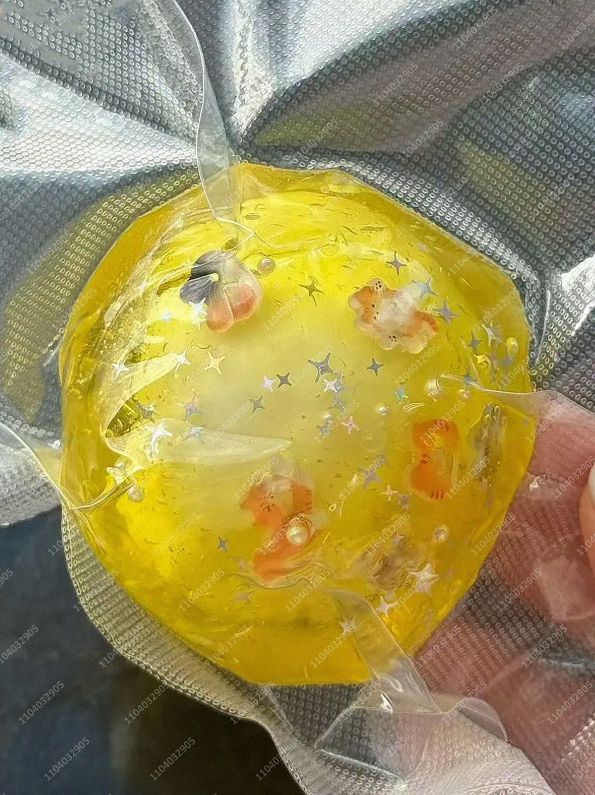 A yellow stress ball is visible inside a clear plastic bag, showing its texture and color.