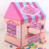 A pink and blue striped foldable kids play tent shaped like a house with a window display of baked goods.