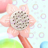 A pink sunflower-shaped bubble blower toy with a large central bubble mechanism and a green bubble in the foreground.