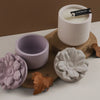 A set of handmade floral silicone molds in lavender and light gray are displayed on a white surface.