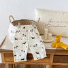 Cream casual pants with a plaid print featuring small dog illustrations displayed on a wooden surface.