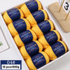 A box containing ten balls of yellow merino wool yarn with blue labels for knitting projects