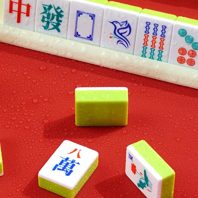 A row of Mahjong tiles and a single green tile are displayed on a red surface.