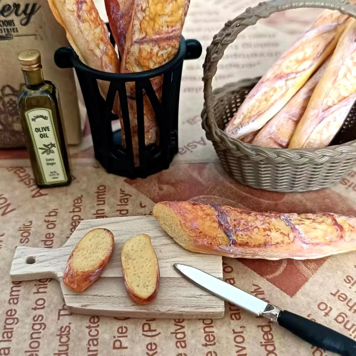 A miniature baguette is shown next to olive oil and a woven basket of bread in a rustic setting.
