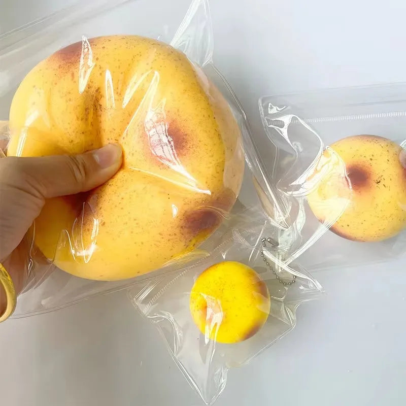 A hand holds a yellow, squishy potato-shaped fidget toy inside a clear plastic bag.