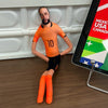 An orange-shirted male figure wearing black shorts and orange boots stands in front of a white cabinet.