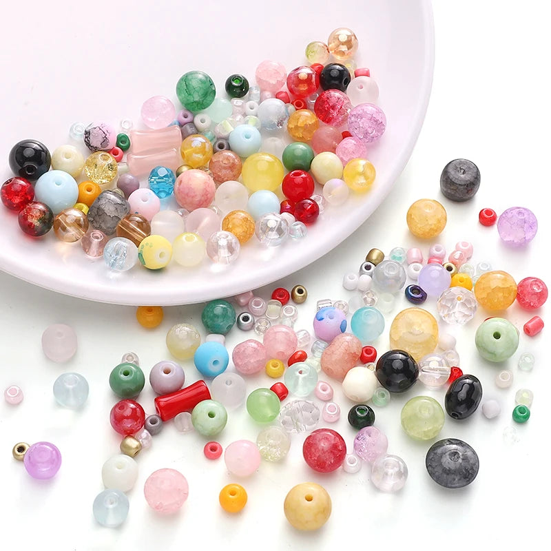 A collection of multicolored glass beads in various shades and sizes scattered on a white surface.
