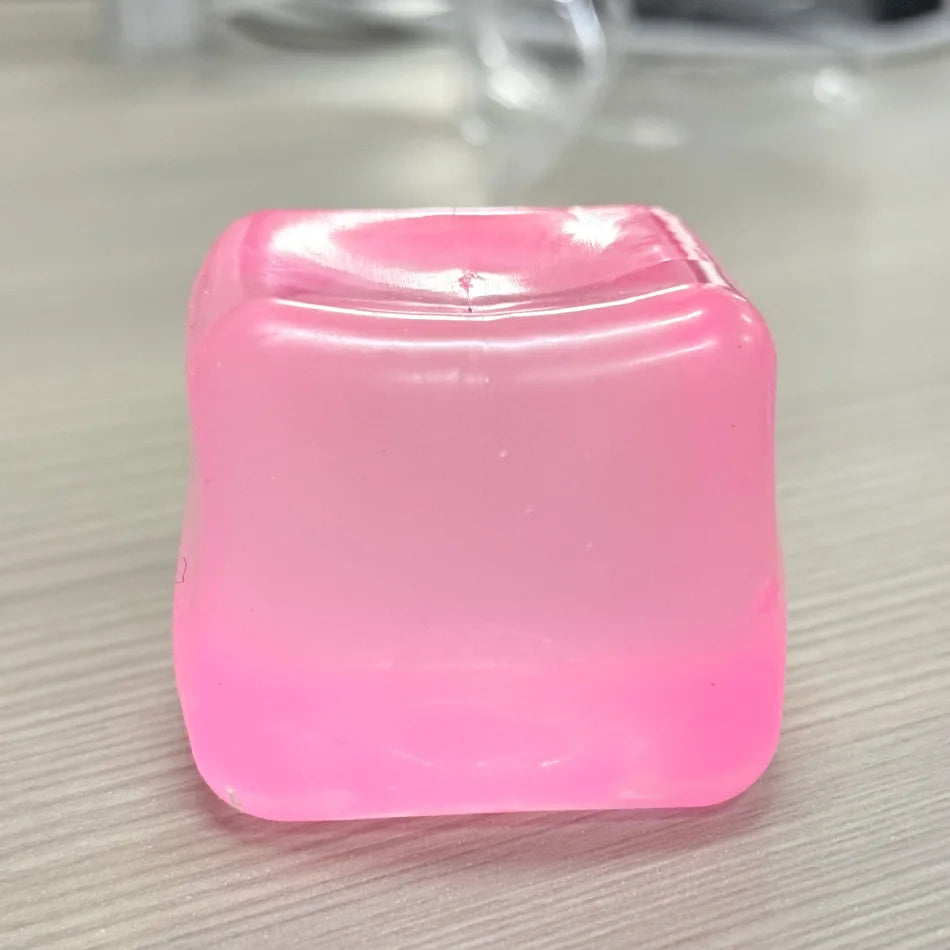 Un cube anti-stress rose carré et moelleux posé sur une surface claire.
