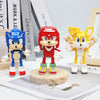 A set of three dinosaur-themed building block toys in blue, red, and yellow standing on a wooden base.