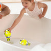 A young girl is placing a yellow swimming frog toy into a white bathtub.