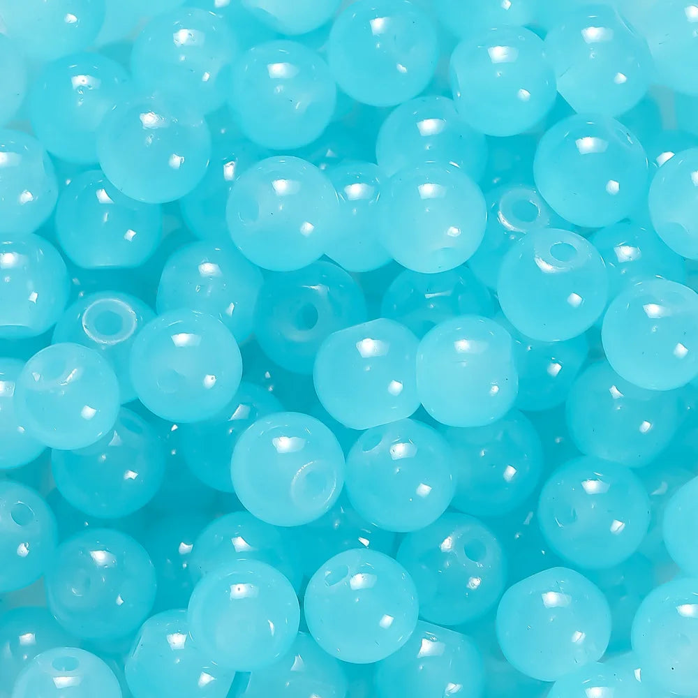 A close-up view of small, round, light blue glass beads for DIY jewelry making.