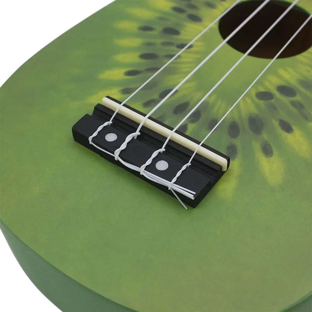 A 21-inch soprano ukulele with a kiwi fruit design is shown, featuring a green body and a black soundboard.