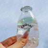 A hand holds a clear plastic bottle filled with liquid and small bubbles, used as a squishy stress ball.