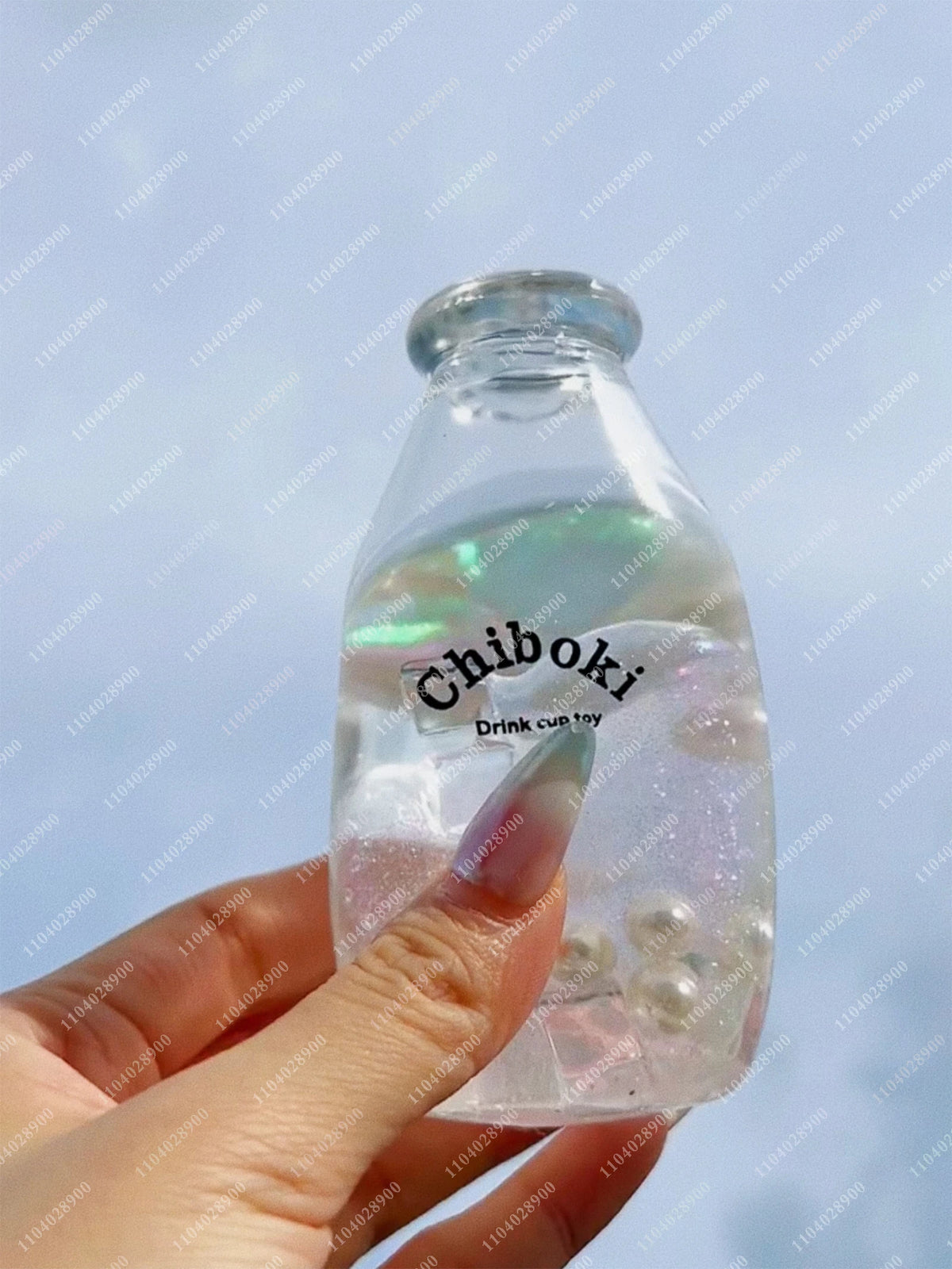 A hand holds a clear plastic bottle filled with liquid and small bubbles, used as a squishy stress ball.