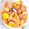 A bowl filled with assorted orange and yellow candy resin flatbacks for DIY crafts and jewelry making