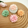 A collection of pink and peach silicone flower molds shaped like carnations resting on a wooden surface.