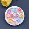 A white silicone mold with various colored daisy flowers for fondant and cake decorating.