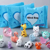 A collection of cute mini animal surprise blind bags in various colors and shapes displayed on a gray surface.