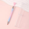 A refillable gradient diamond picking pen with a pink and blue gradient barrel and a pink wax tip resting on a light pink sur