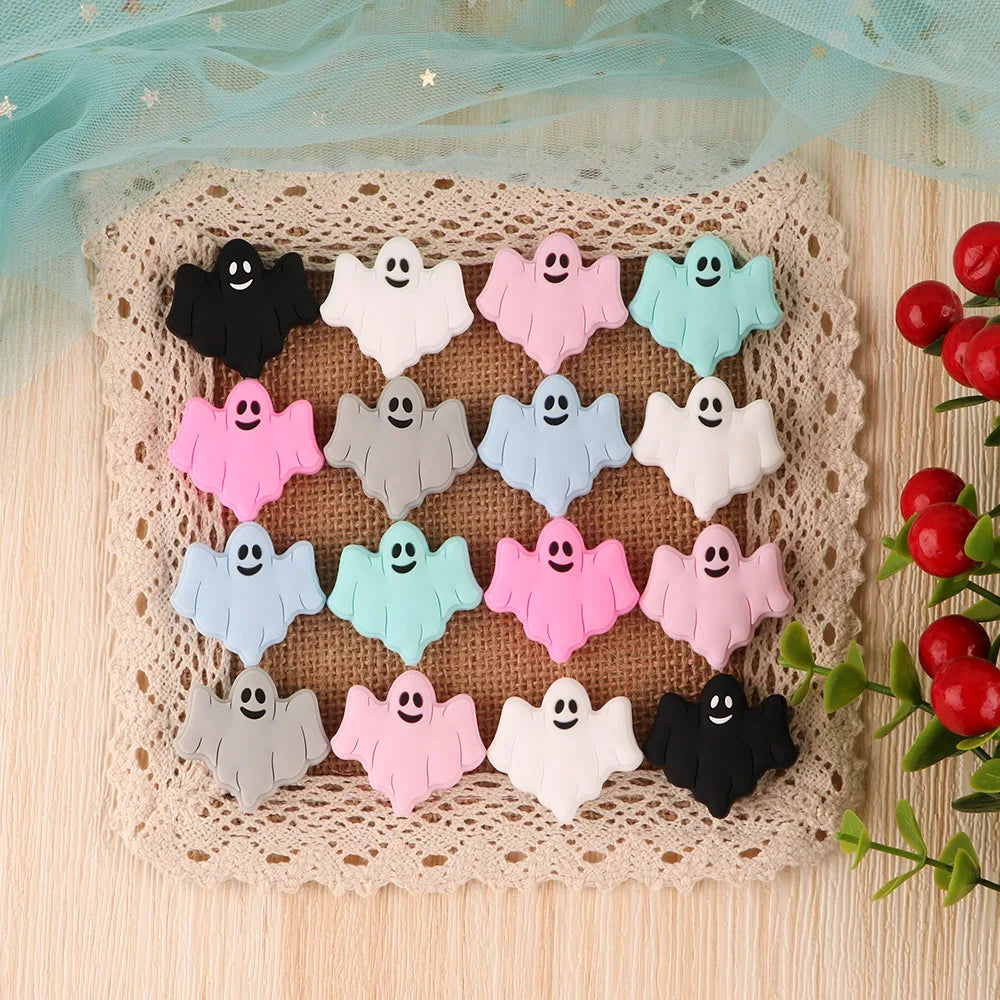A set of five silicone ghost beads in various pastel colors including pink, blue, green, and white, displayed on a woven mat.