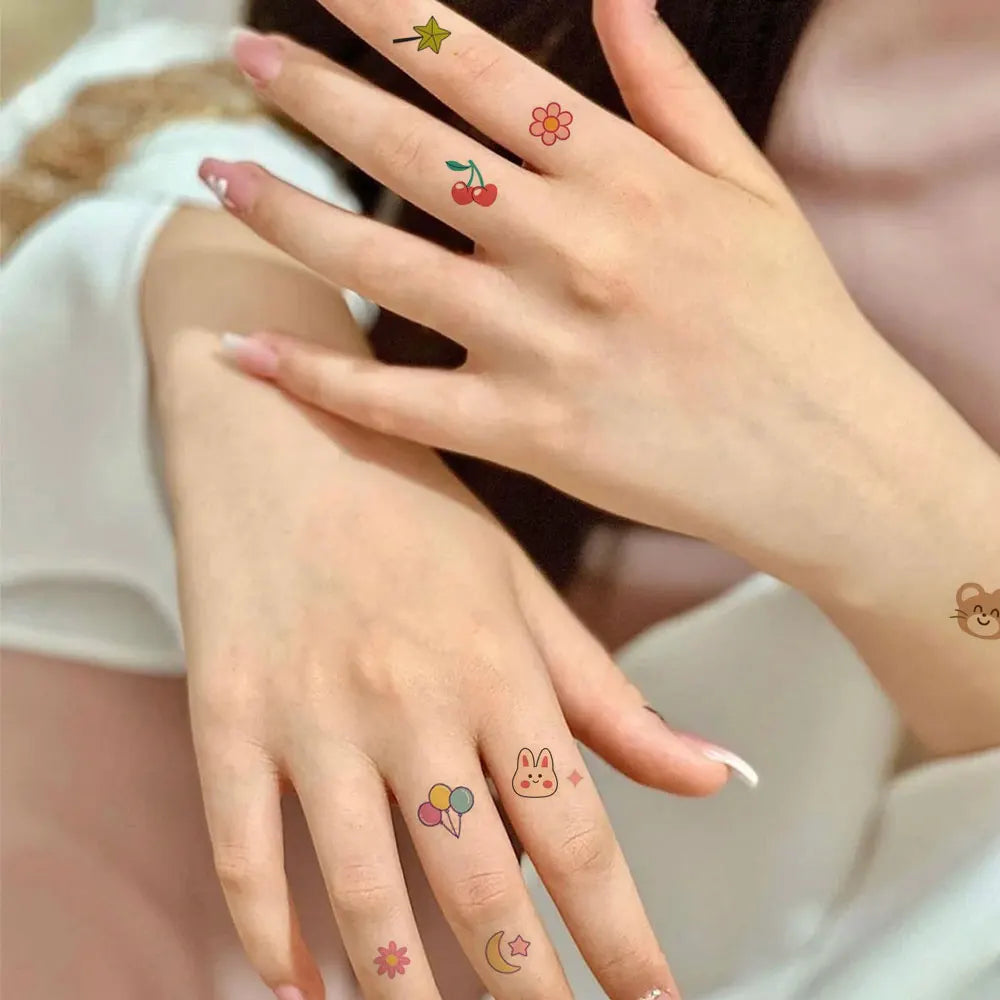 A close-up of a hand with temporary tattoos on the fingers, showing various colorful designs.