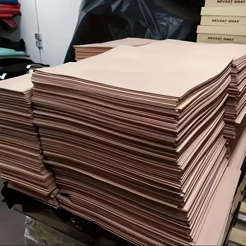 A stack of natural vegetable-tanned cowhide leather sheets for crafting in various shades of tan and brown.