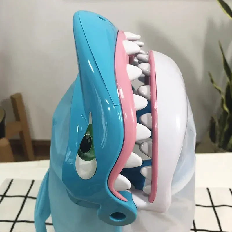 A blue shark-shaped board game toy featuring teeth and a snout, used for family fun.