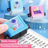 A hand holds a blue math stamp featuring an astronaut and planets, used for teaching math concepts.