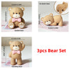 A set of three adorable bear figures in a light tan color, including seated, lying down, and standing poses.