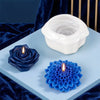 White silicone candle mold with a floral design and a blue silicone flower mold on a light blue surface.