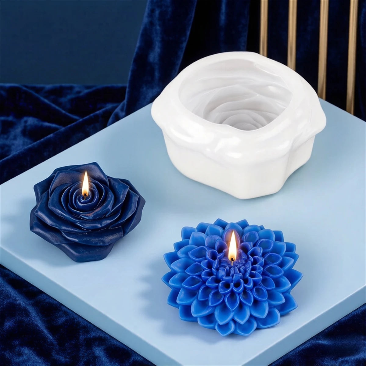 White silicone candle mold with a floral design and a blue silicone flower mold on a light blue surface.