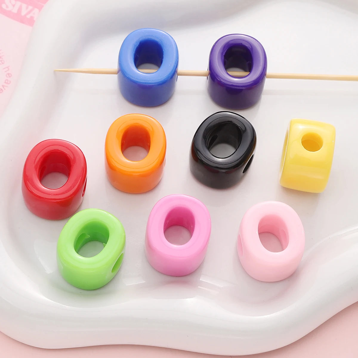 A collection of colorful acrylic letter beads in various colors like blue, purple, orange, black, yellow, and pink arranged o