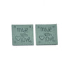 Two gray embossed leather labels with the text Made with Love and a heart symbol.