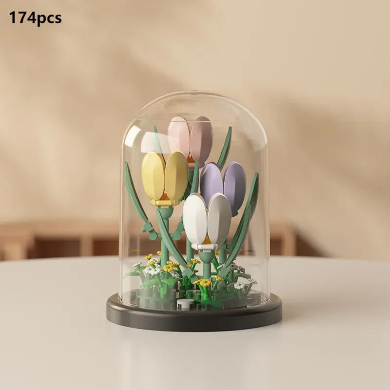 A clear glass container holds 174 plastic flower building blocks in various shades of pink, yellow, and purple.