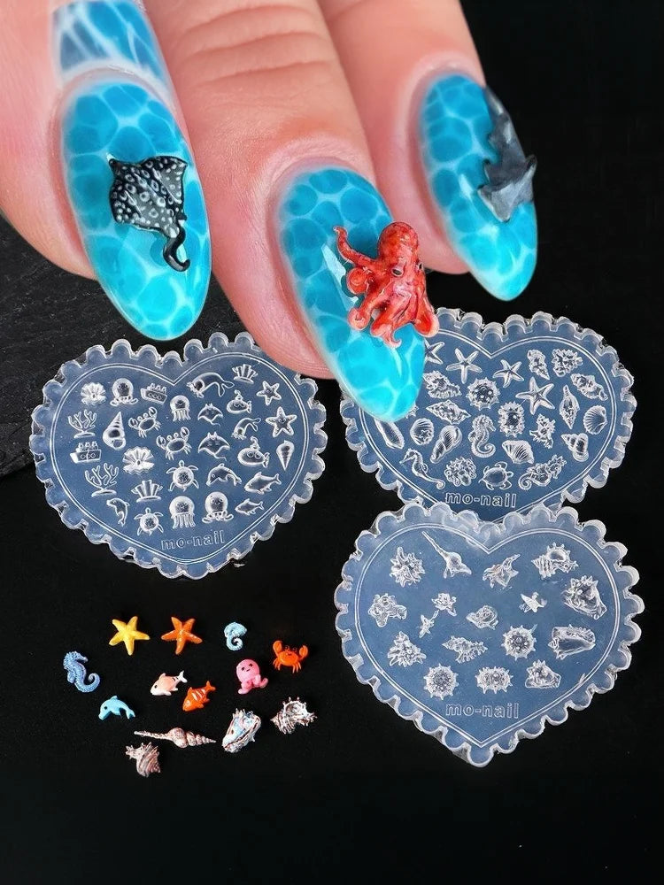 A hand displays various 3D silicone nail art molds featuring sea shell, starfish, and ocean designs.