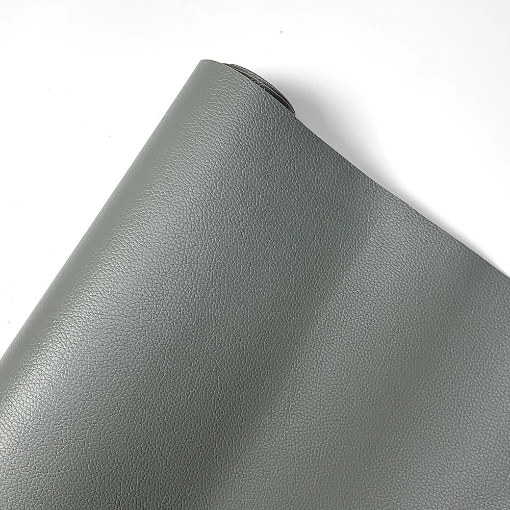 A close-up view of a gray PU leather material rolled up, showing the texture and finish.