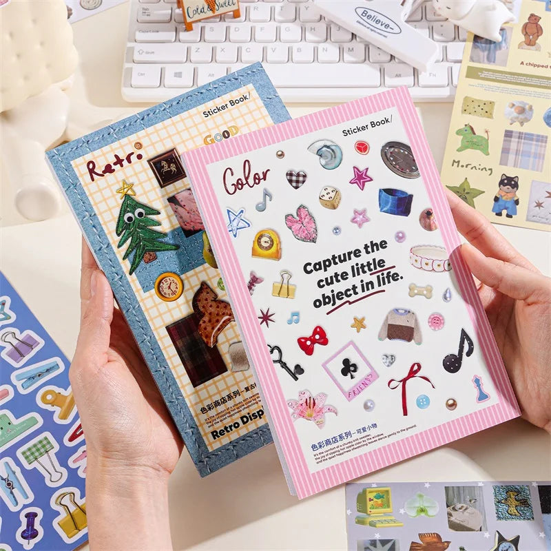 A hand holds an open sticker book featuring retro aesthetic stickers and craft supplies.