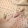 Close-up of sparkling 5D diamond nail art stickers and pearl strands displayed on a pink background.