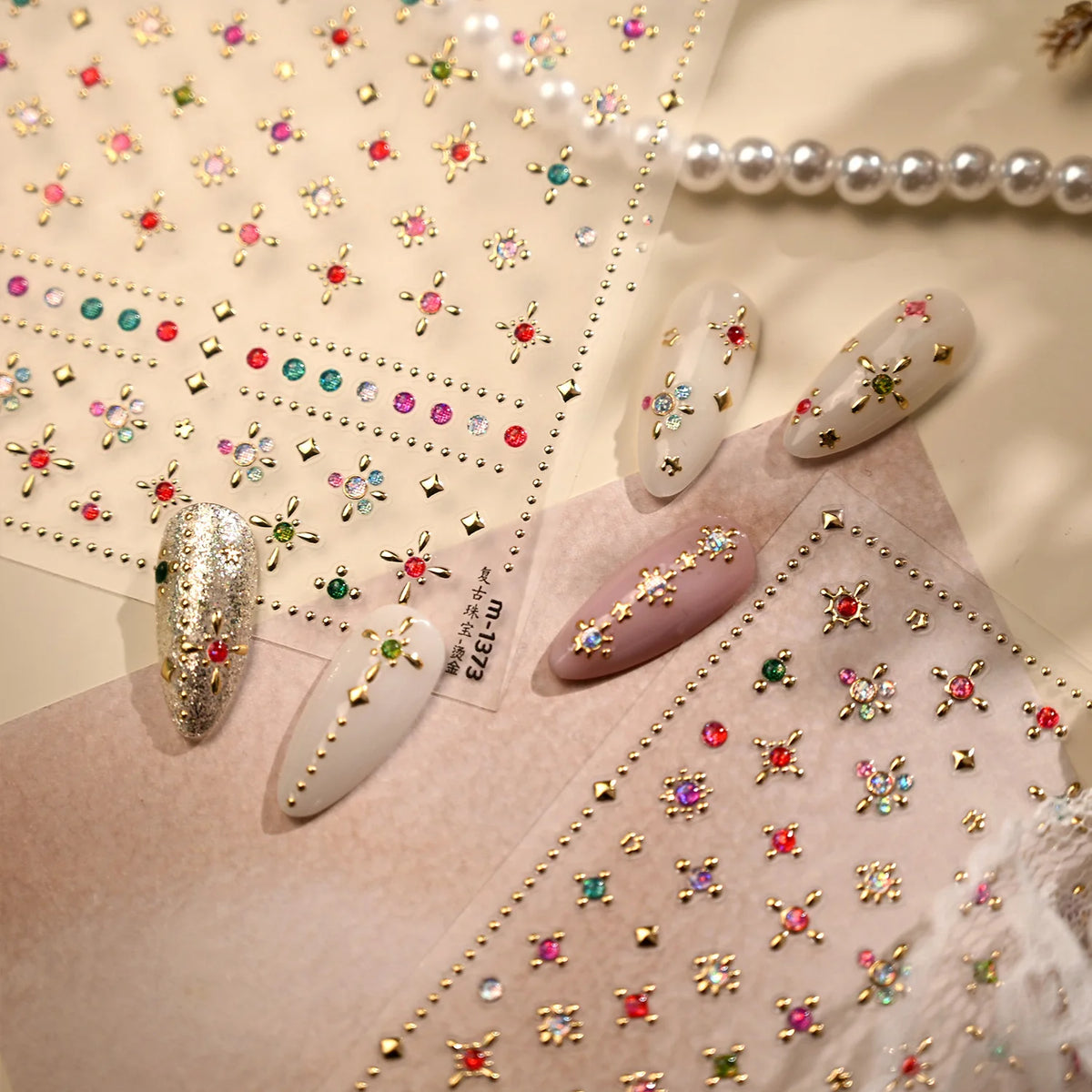 Close-up of sparkling 5D diamond nail art stickers and pearl strands displayed on a pink background.