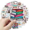 A hand holds a stack of cartoon bookworm reading stickers featuring various literary titles and illustrations.
