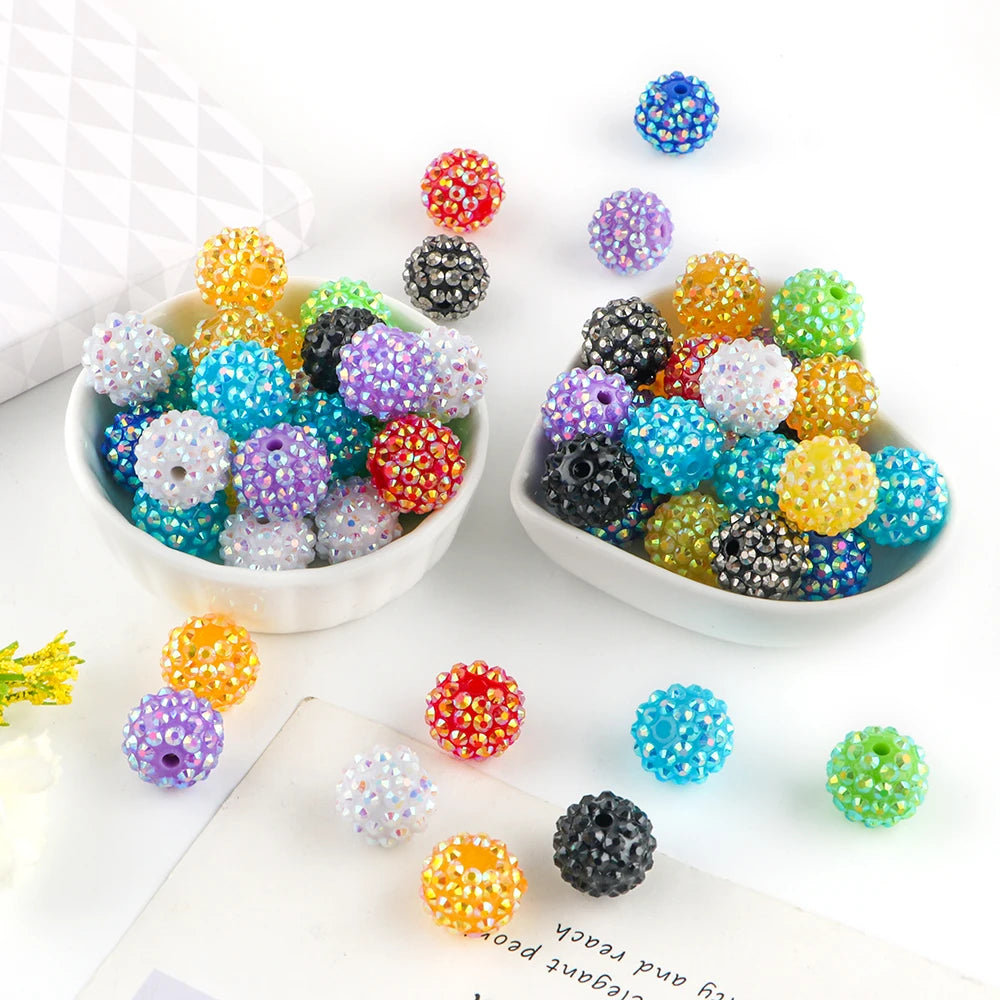 A collection of colorful rhinestone resin bayberry beads in various shades and sizes displayed on a white surface.