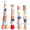 Un ensemble de blocs de construction sensoriels en bois dans diverses teintes pastel et bois naturel, empilés verticalement.