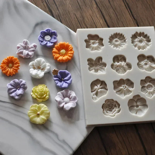 A collection of silicone flower molds in various shades of orange, purple, and white are displayed on a white marble surface.