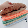 A stack of cozy lamb wool baby vests in various shades of brown, orange, green, and blue.
