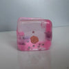 A translucent pink squishy stress ball shaped like a cube, decorated with stars and a seashell.